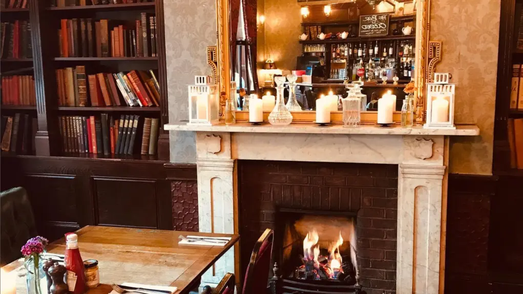 Wooden table in pub set for Sunday lunch in front of a open fire
