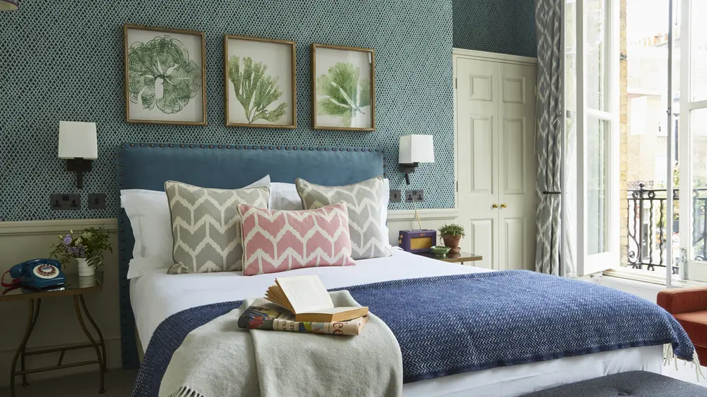 A hotel room with a bed and three botanical prints on the wall at the Lime Tree Hotel in Belgravia