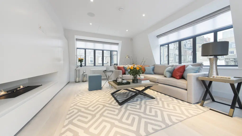 A living room with a sofa, coffee table and fire