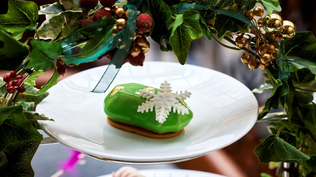 A cake with a snowflake decoration on a tiered cake tray with holly
