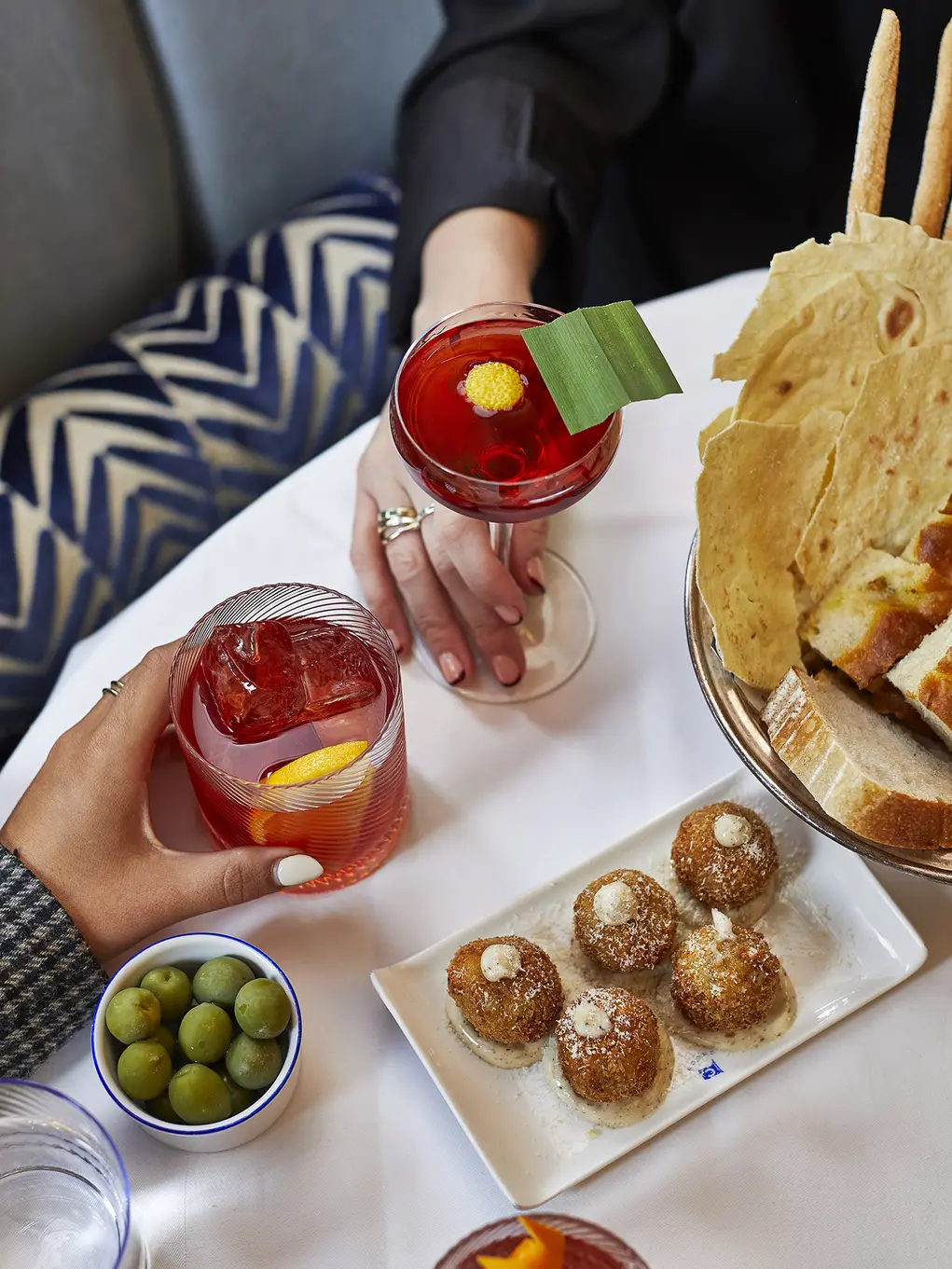 Dishes of food and two red cocktails