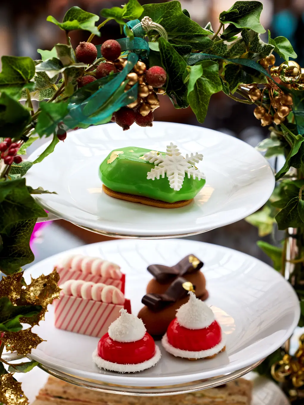 A tiered cake tray with Christmas cakes and holly