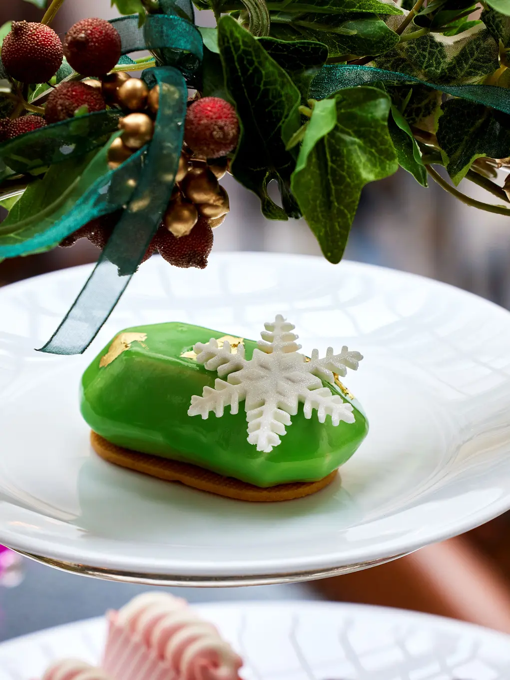 A cake with a snowflake decoration on a tiered cake tray with holly