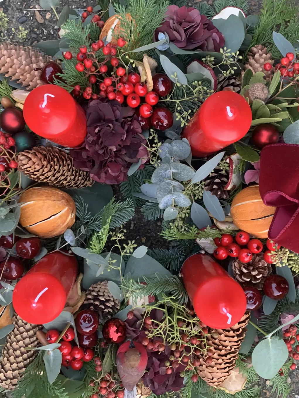 A Christmas wreath with four red candles and a red bow