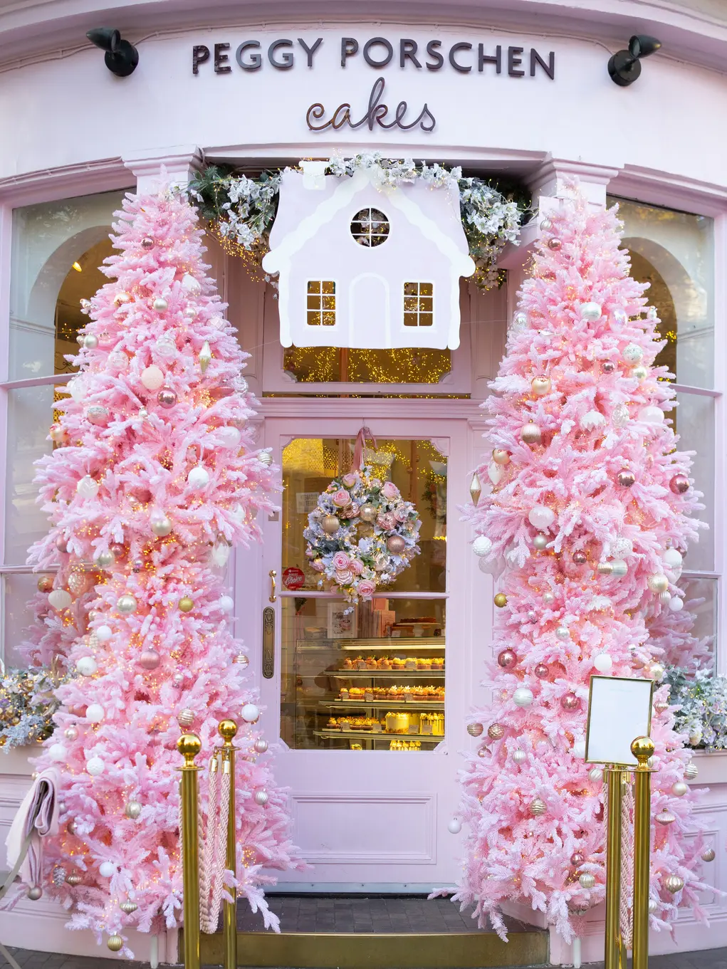 The outside of Peggy Porschen flanked by two pink Christmas trees