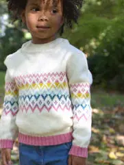 A little girl wearing a white wool jumper
