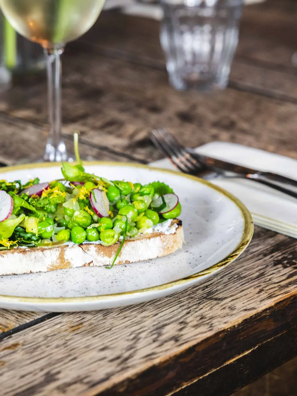 Plate with toast and avocado and a glass of white wine