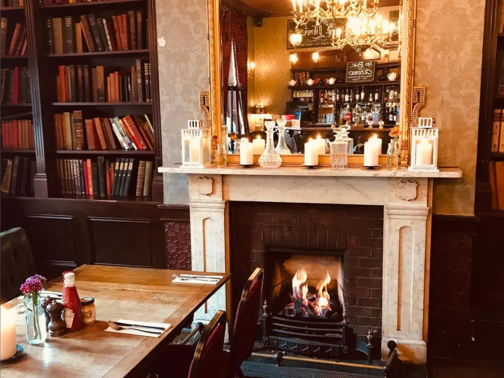 Wooden table in pub set for Sunday lunch in front of a open fire