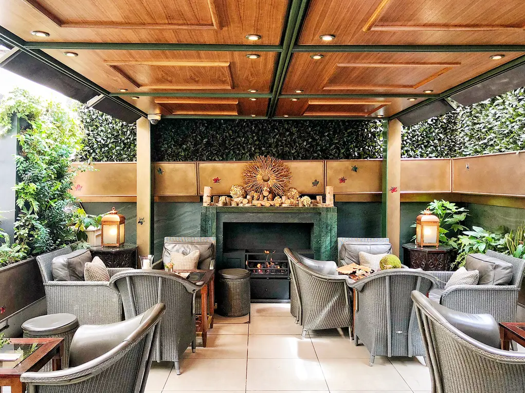 The Garden Room at The Lanesborough with chairs, tables and a fireplace