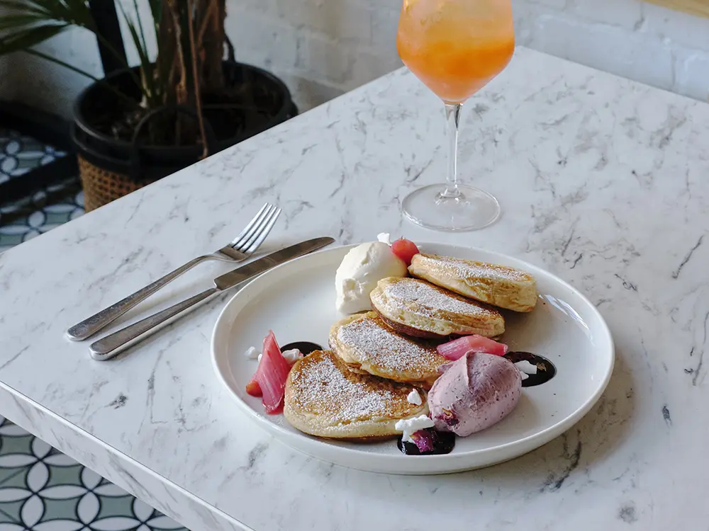 A plate of pancakes and a tropical drink in a cocktail glass with a straw