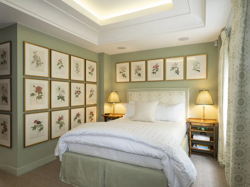 A bedroom with a bed with two bedside tables and lots of pictures on the walls