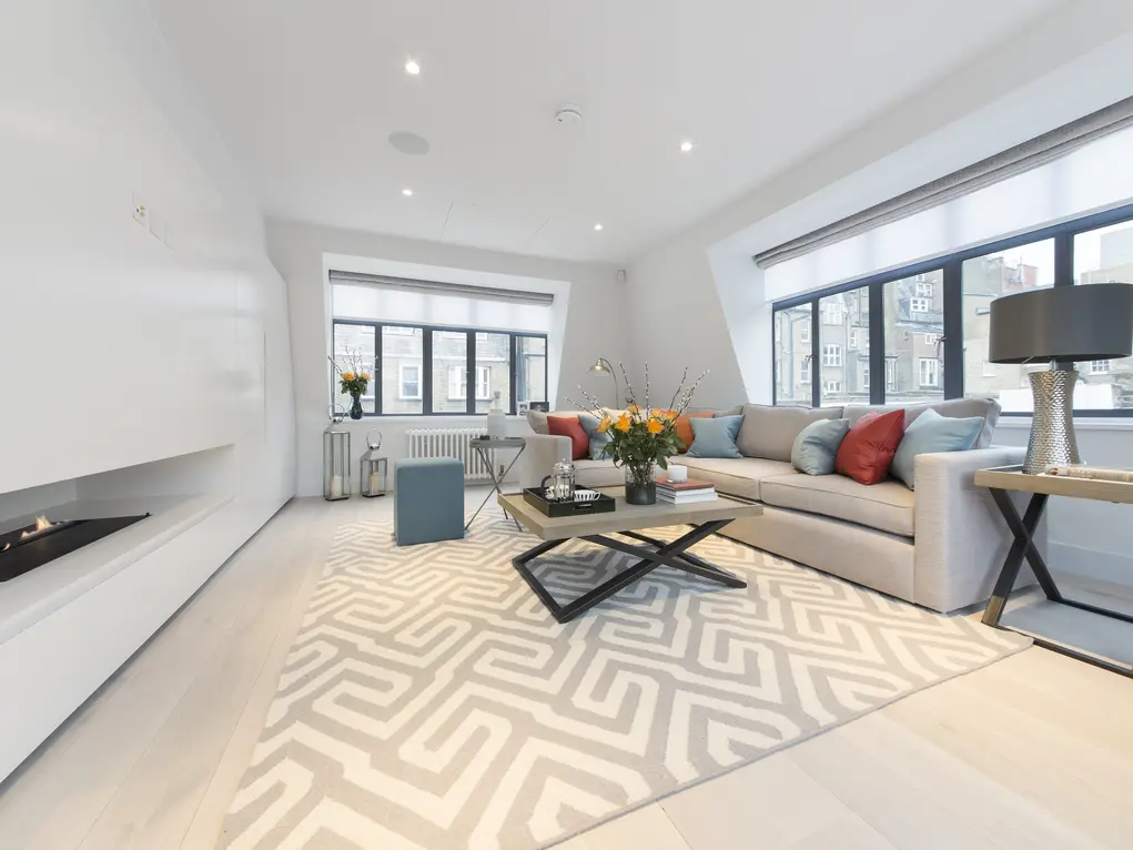 A living room with a sofa, coffee table and fire