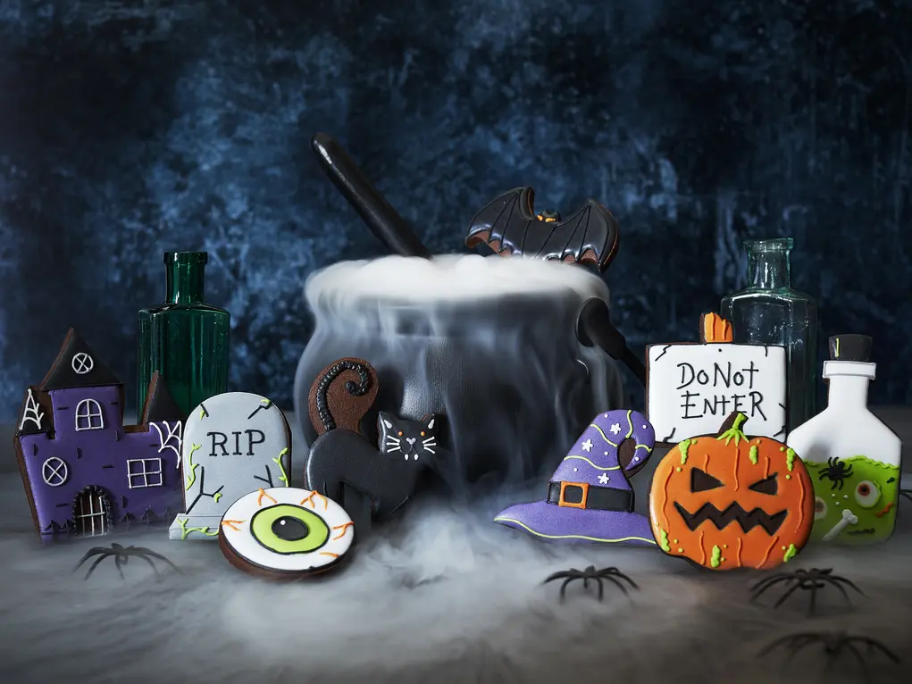 A cauldron surrounded by Halloween biscuits including a pumpkin, witch's hat and haunted house