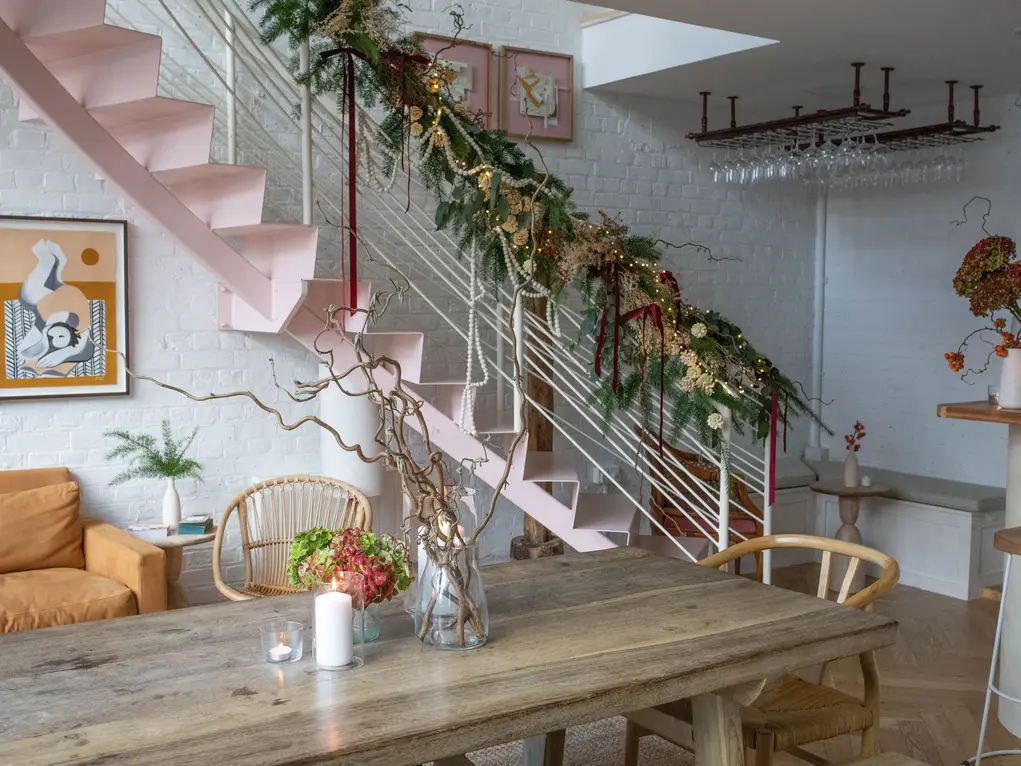 The inside of Amie Wine Studio with a large wooden table and stairs with festive decorations