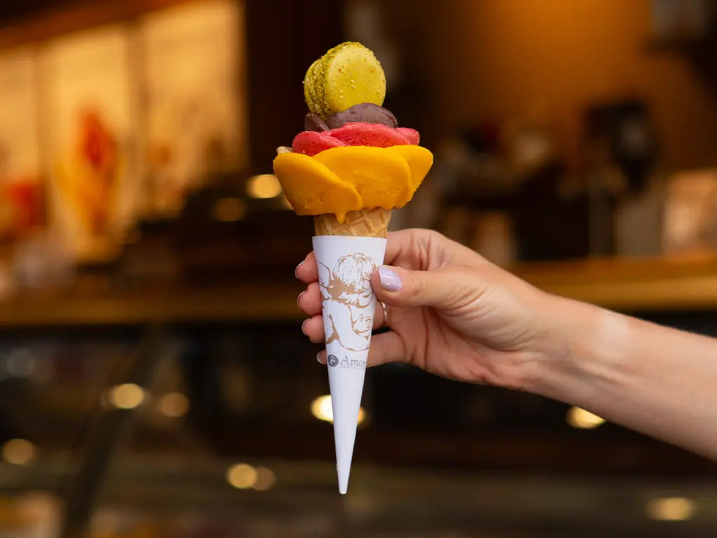A hand holding an ice cream in a cone
