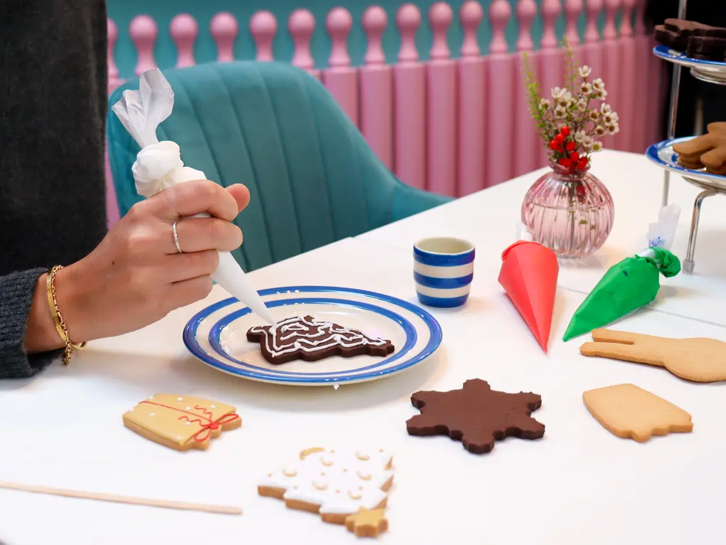 A person icing a Christmas tree biscuit