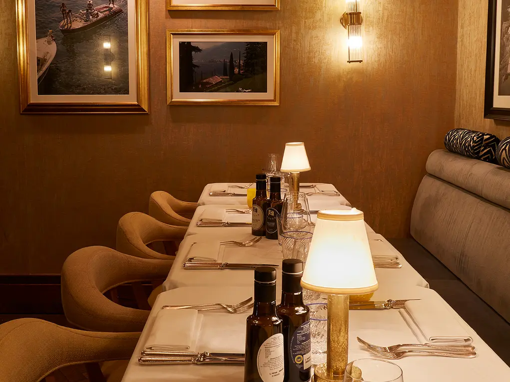 A long dining table with small lamps and pictures on the wall