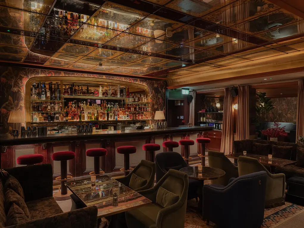 Inside of Luum bar with a long bar area and large velvet sofas