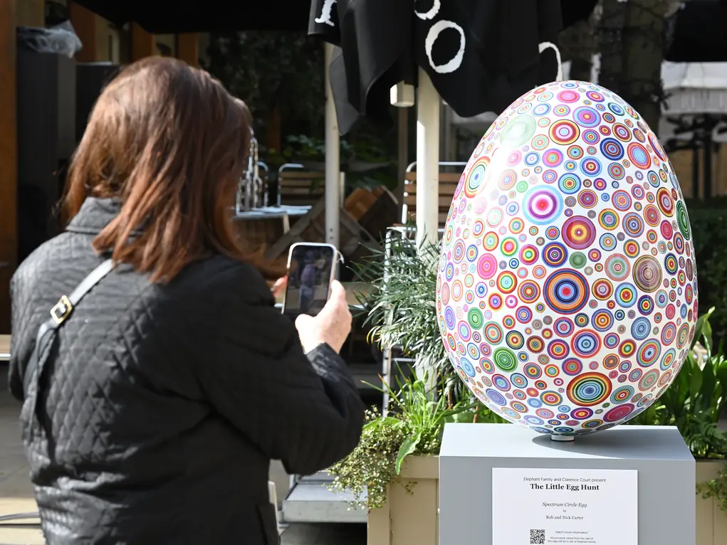 woman takes photo of egg decorated in circle patterns 