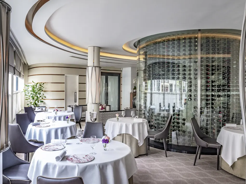 A restaurant with circular tables with white tablecloths