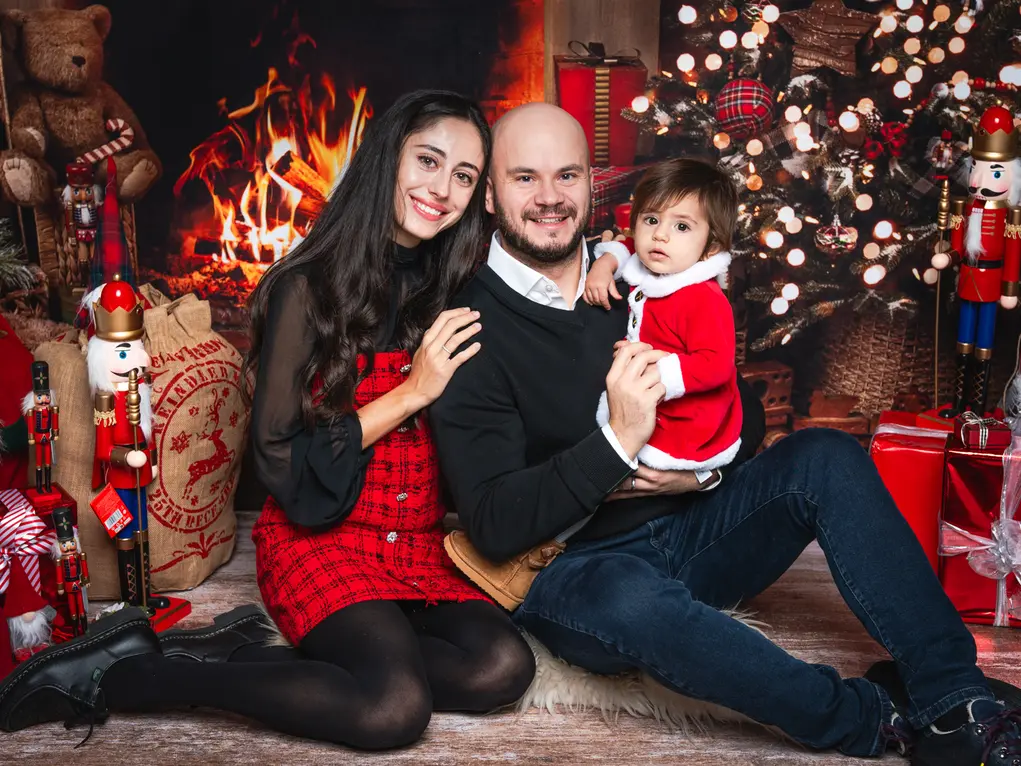 A family of three sitting in front of the fire with presents 